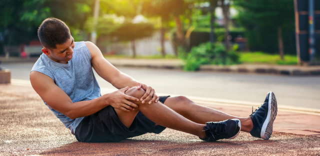 Runner on a track clutching their knee in pain after an injury